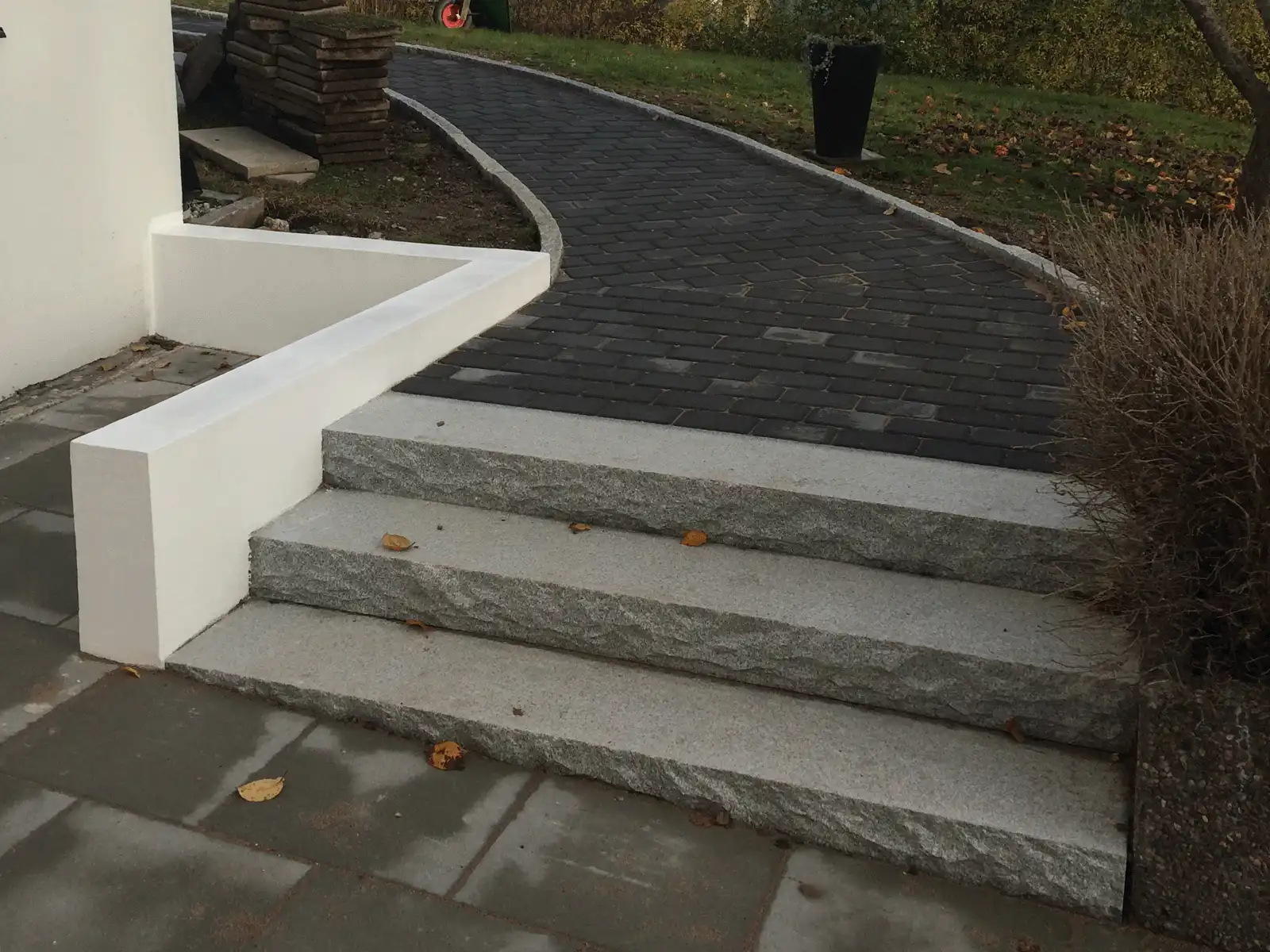 Bilden visar en stilren trappa i granit med en vit betongkant som ger en modern och elegant look. Stenläggningen är väl utförd med jämna steg, och den raka designen gör den perfekt för både privata och offentliga utrymmen. Den omgivande gångvägen av sten och den noggrant utformade trappan ger en harmonisk och funktionell ingång till byggnaden. Bilden visar en stilren trappa i granit med en vit betongkant som ger en modern och elegant look. Stenläggningen är väl utförd med jämna steg, och den raka designen gör den perfekt för både privata och offentliga utrymmen. Den omgivande gångvägen av sten och den noggrant utformade trappan ger en harmonisk och funktionell ingång till byggnaden.